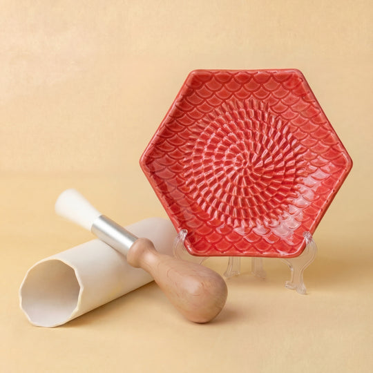 red ceramic grating plate with garlic peeler and brush